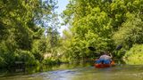 Zwei Menschen in einem Boot paddeln durch eine grüne Landschaft