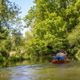 Zwei Menschen in einem Boot paddeln durch eine grüne Landschaft
