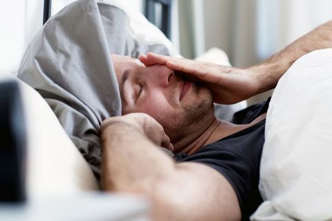 Müder Mann liegt im Bett