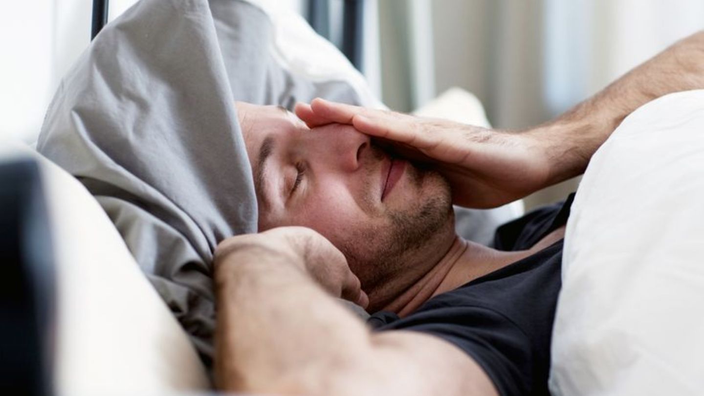 Müder Mann liegt im Bett
