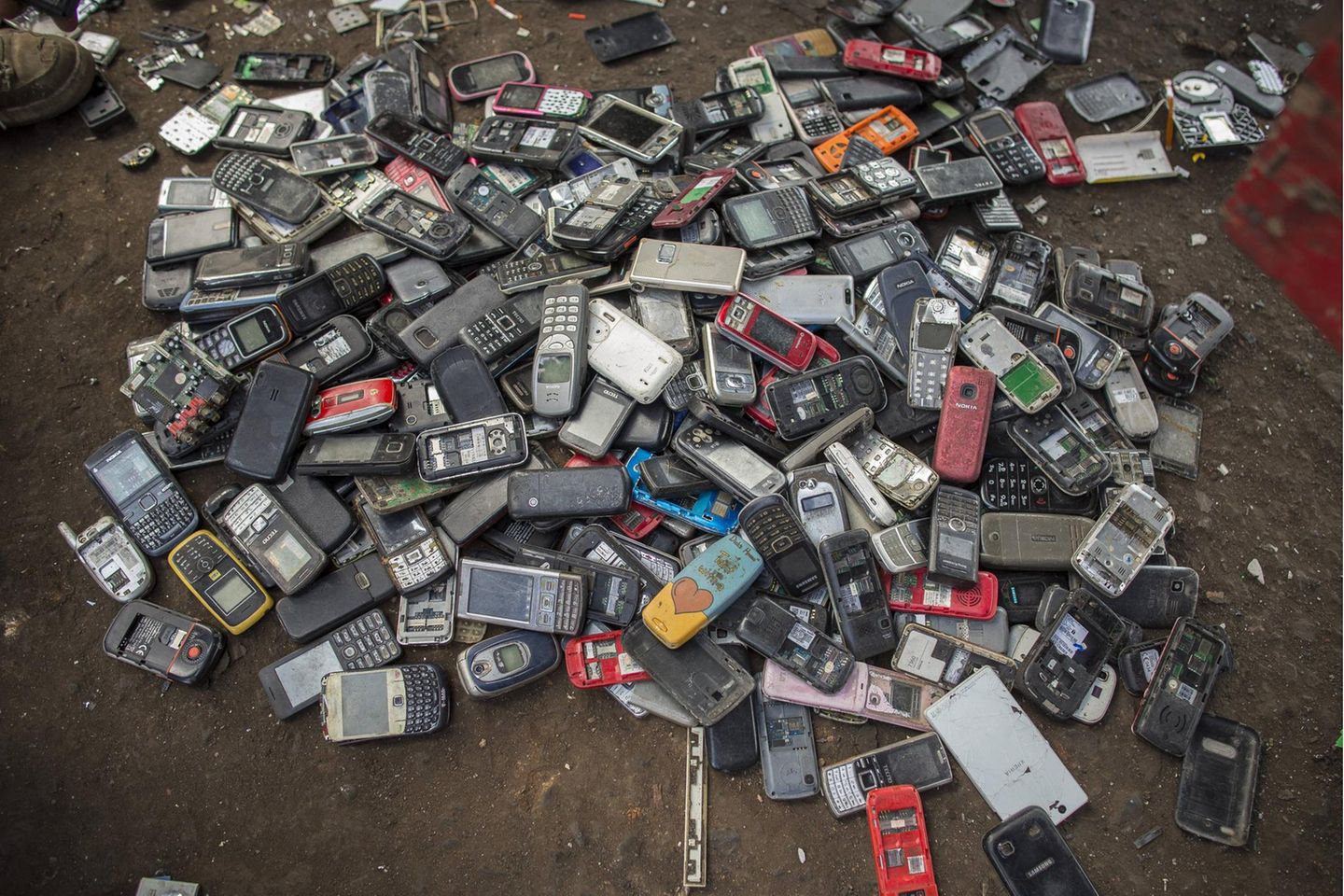 Ein Berg voller Smartphones liegt auf einem dreckigen Boden