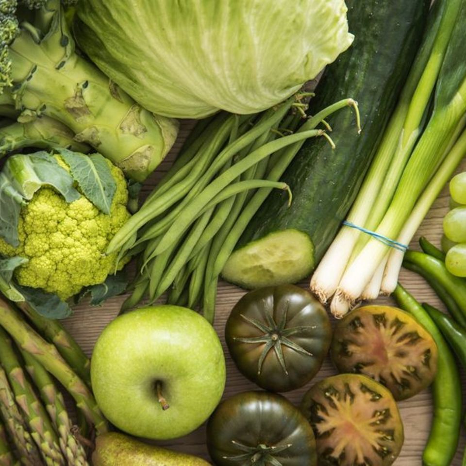 Grünes Gemüse und Obst auf einem Holztisch