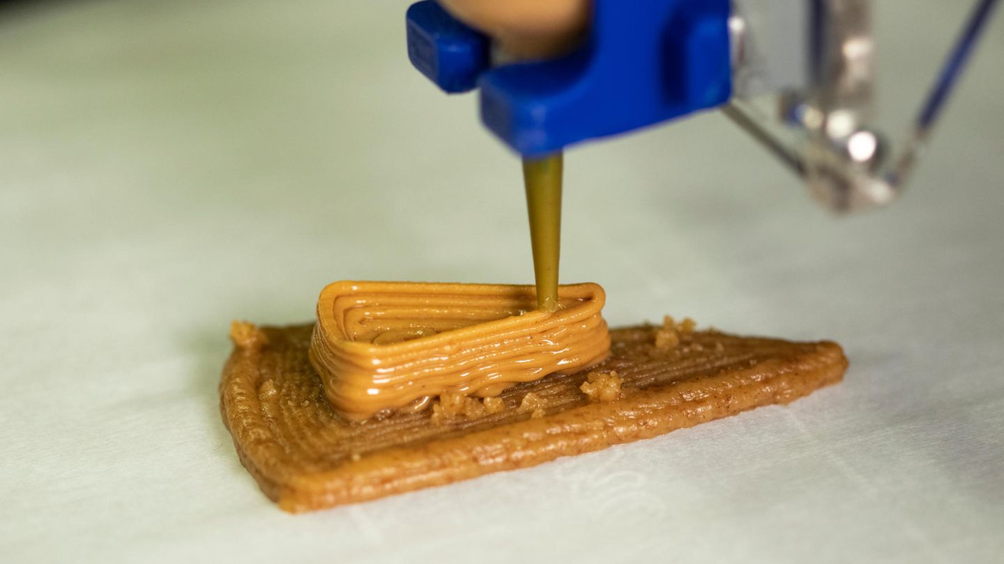 Ein 3D-Drucker spritzt eine braune Masse in Kuchenform