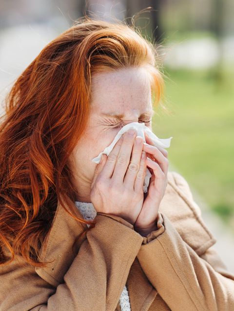 Junge Frau niest in ein Taschentuch