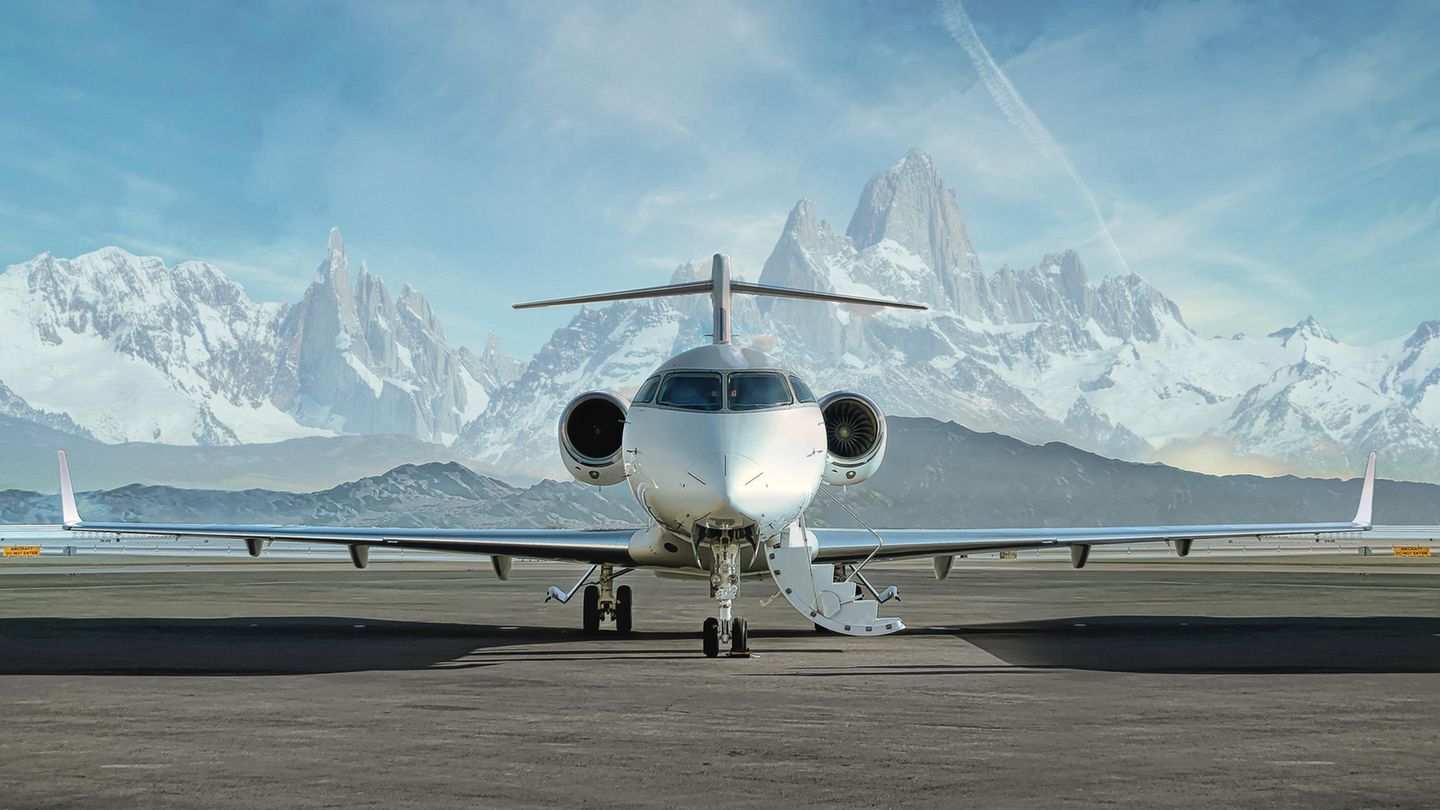 Privat Jet steht zum Einstiegen bereit, dahinter verschneite Gipfel