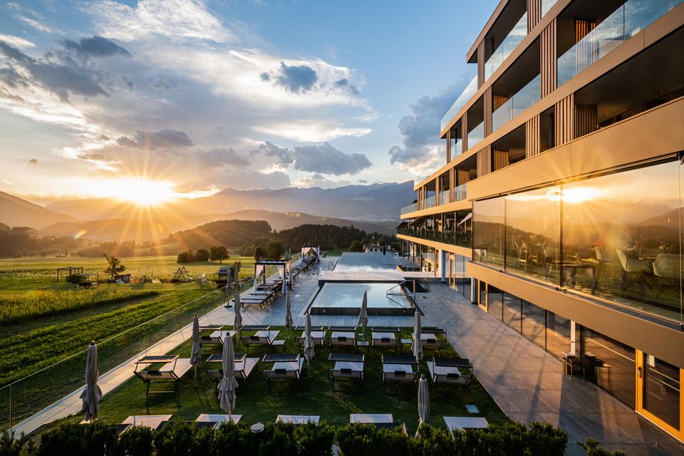 Die Sonne geht auf und spiegelt sich im Pool und der Glasfront des Hotel Winkler in Südtirol
