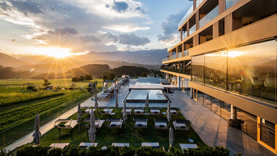 Die Sonne geht auf und spiegelt sich im Pool und der Glasfront des Hotel Winkler in Südtirol