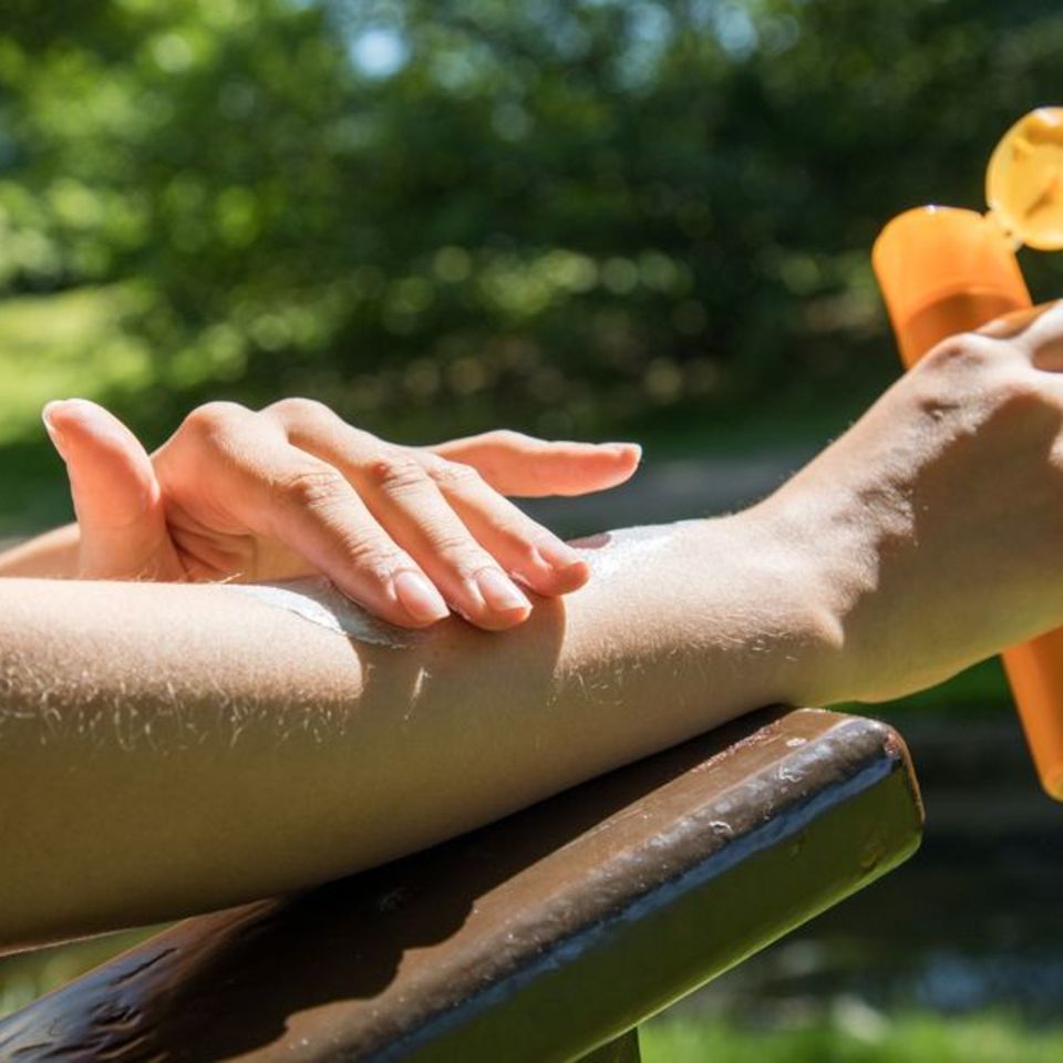 Frau trägt Sonnencreme auf den Unterarm auf