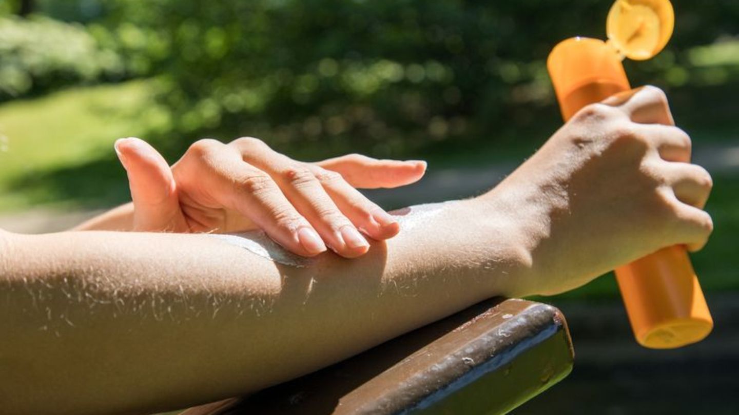 Frau trägt Sonnencreme auf den Unterarm auf
