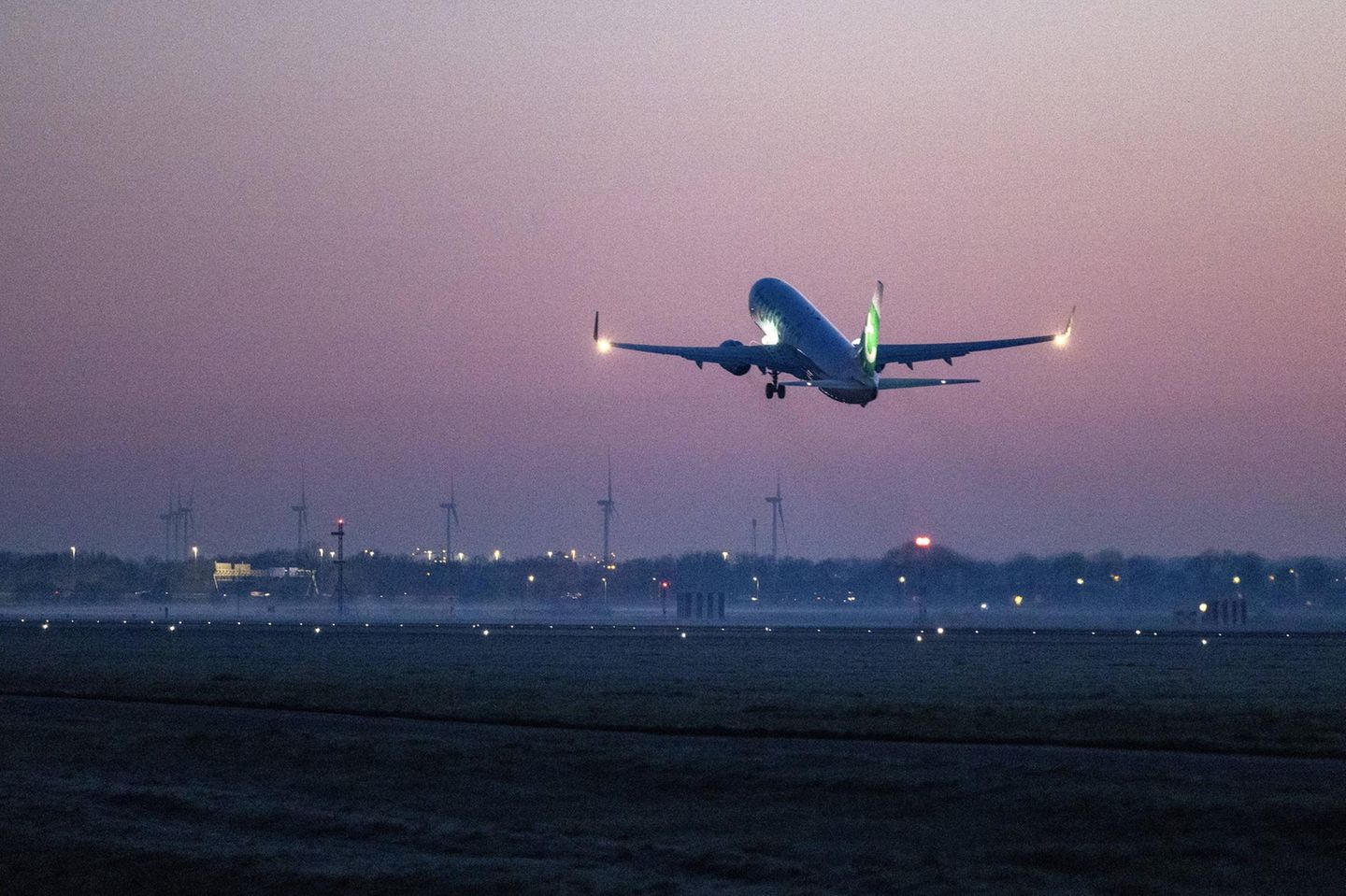 Flugzeug startet bei Nacht am Flughafen Schipohl