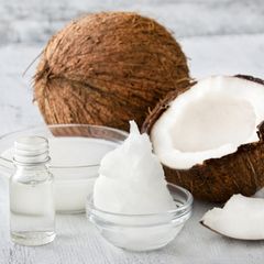 Kokosöl gegen Zecken in einer kleinen Schüssel vor einer Kokosnuss