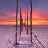 Schmaler Holzsteg am Strand bei Sonnenuntergang