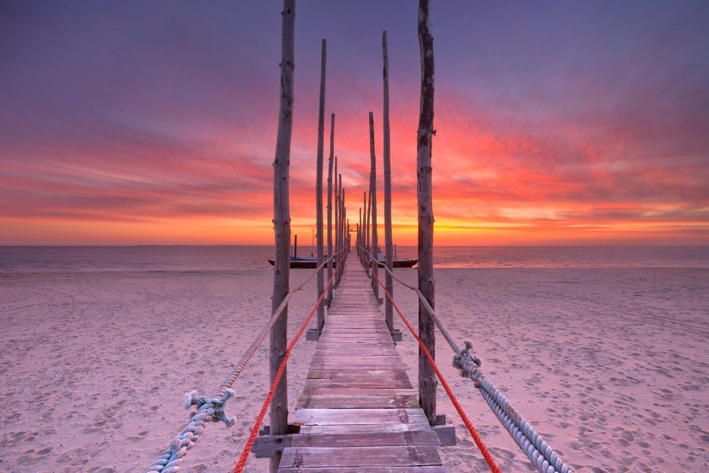 Schmaler Holzsteg am Strand bei Sonnenuntergang