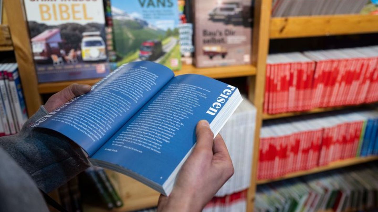 Mann blättert in Reiseführer in der Buchhandlung