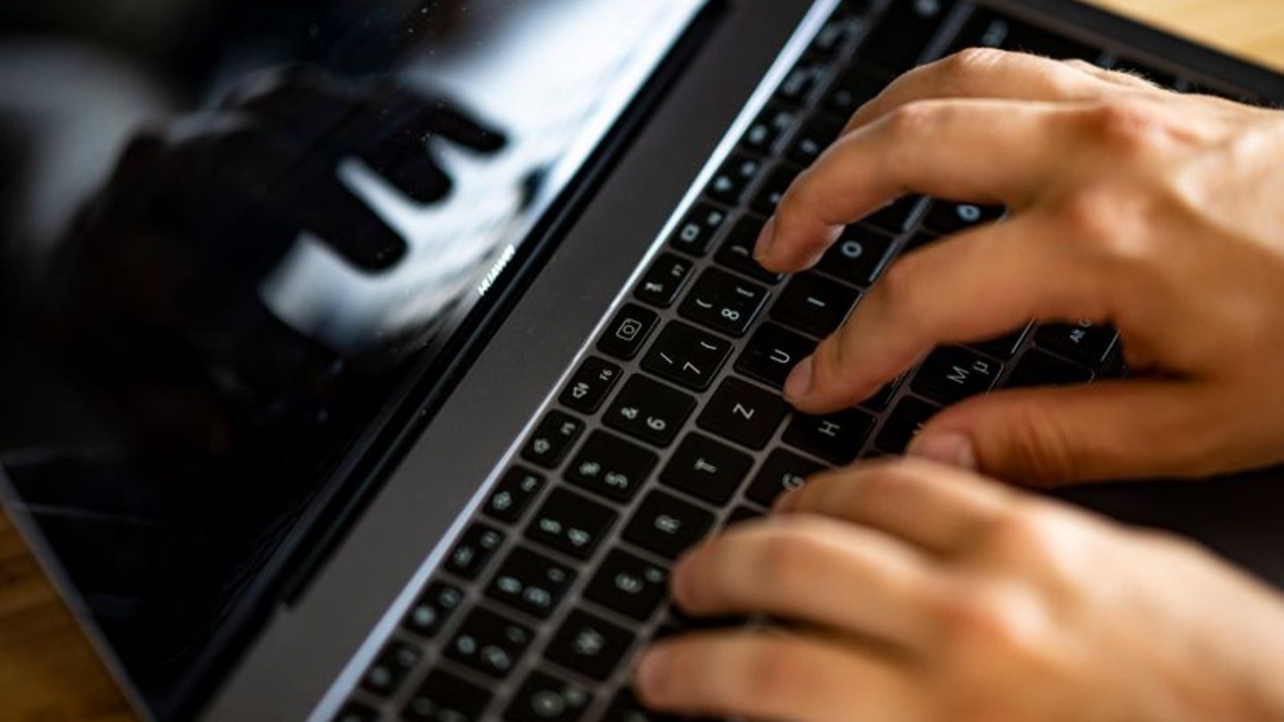 Ein Mann tippt auf einer Tastatur eines Laptops
