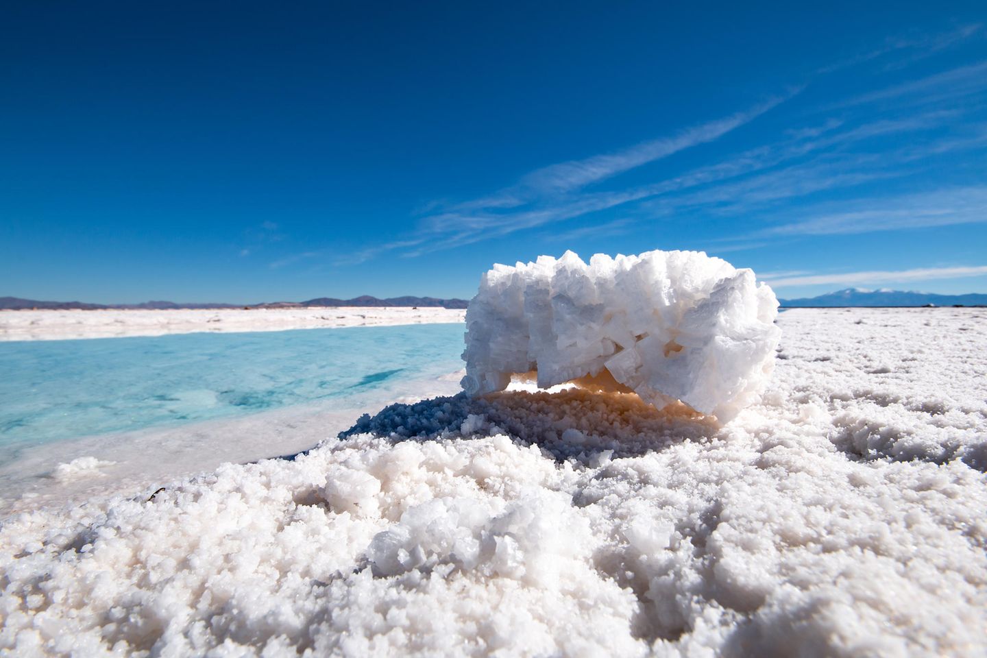Lebenswichtig trifft lebensfeindlich – Salinas Grandes Salzsee mit vielen Salzkristallen bei blauem Himmel