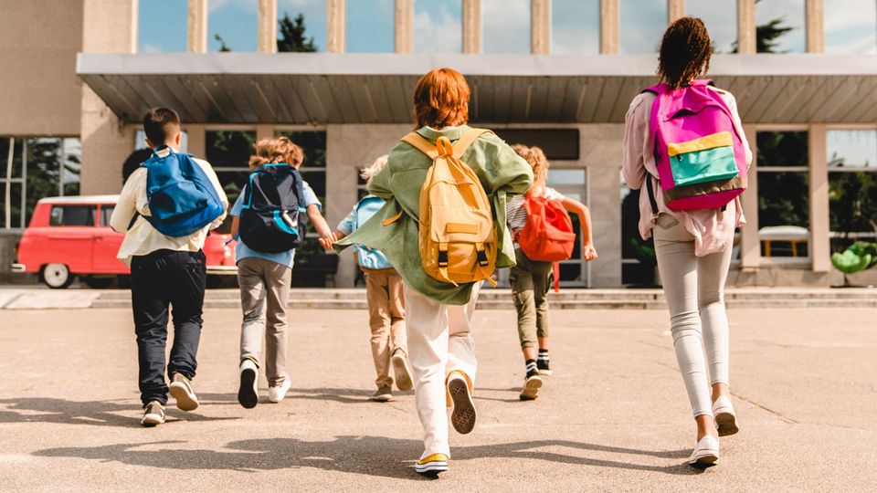 Kinder laufen auf ein Schulgebäude zu - für Eulen ist ein früher Schulbeginn oft anstrengend