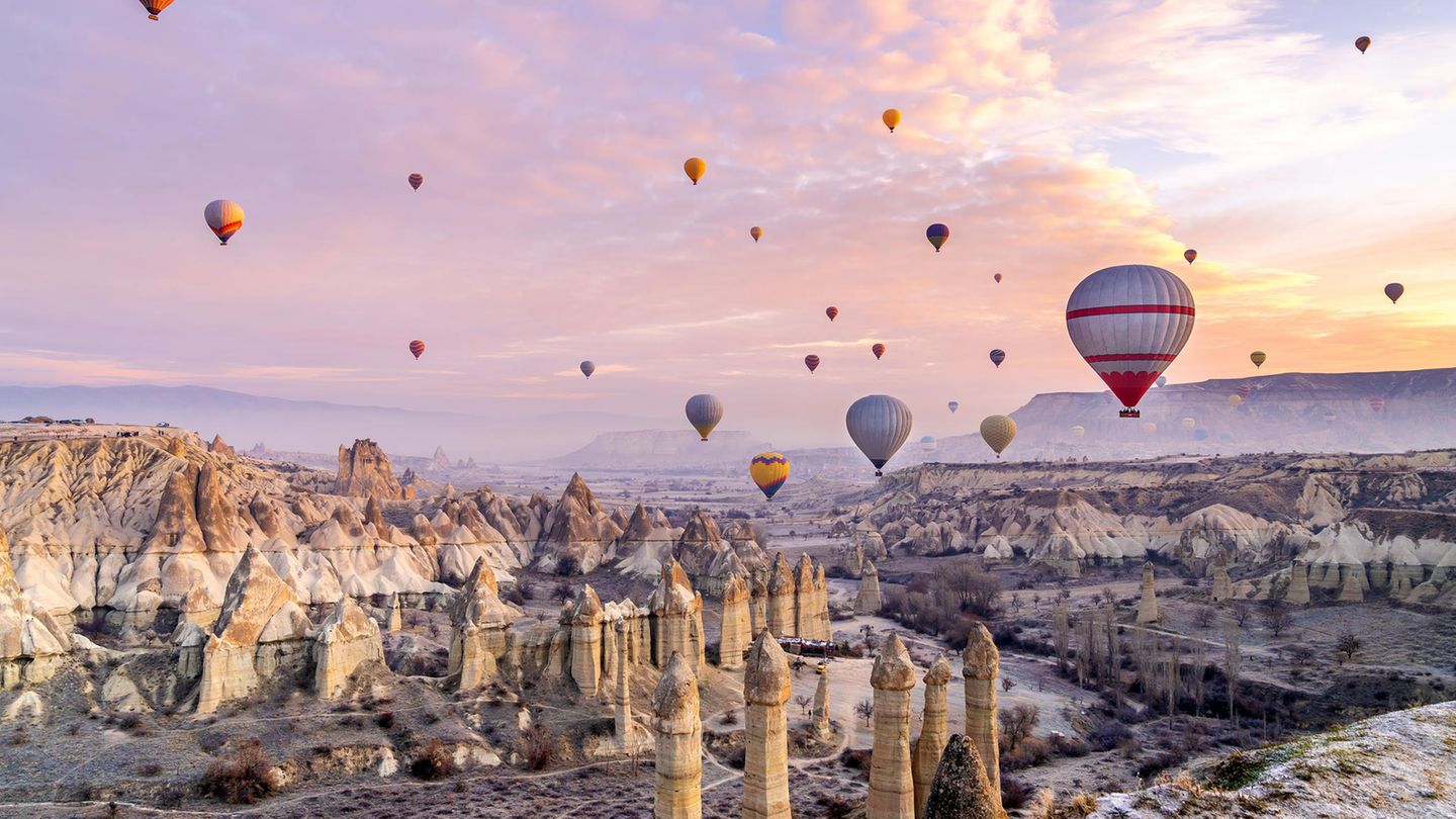 Bunte Heißluftballons über einer großen Felsenformation in Kappadokien