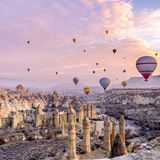 Bunte Heißluftballons über einer großen Felsenformation in Kappadokien