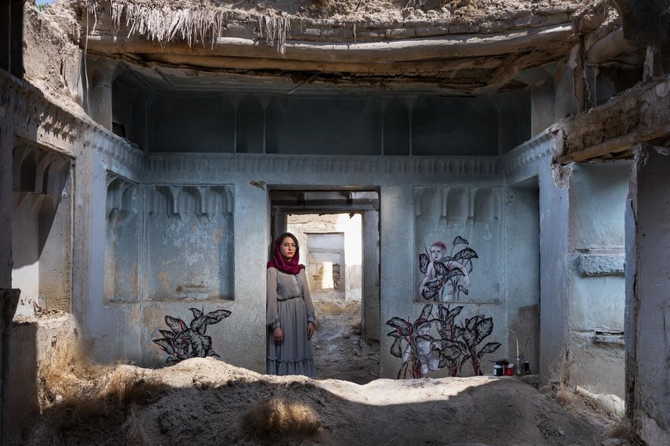 Pooneh Oshidari, geboren 1984 in Teheran  Das Haus mitten in Teheran ist rund 150 Jahre alt. Doch seit 40 Jahren steht es verlassen da, verfällt. Nur der Zierrat an den Mauern lässt noch erahnen, wie schön es einmal gewesen sein muss. Der Besitzer hat das Land verlassen und in den USA ein neues Leben angefangen. Nun hat die Künstlerin Pooneh Oshidari auf den blanken Wänden ein Bild der Zuversicht gemalt: Pflanzen recken ihre Blätter in die Höhe, so kraftvoll, dass Kinder auf ihnen klettern können. Allerorten erlebt die Künstlerin, wie Wasserknappheit im Iran die Landschaft verdorren lässt. Und so hat sie die Bedrohung der Umwelt zum Kern ihres Schaffens gemacht