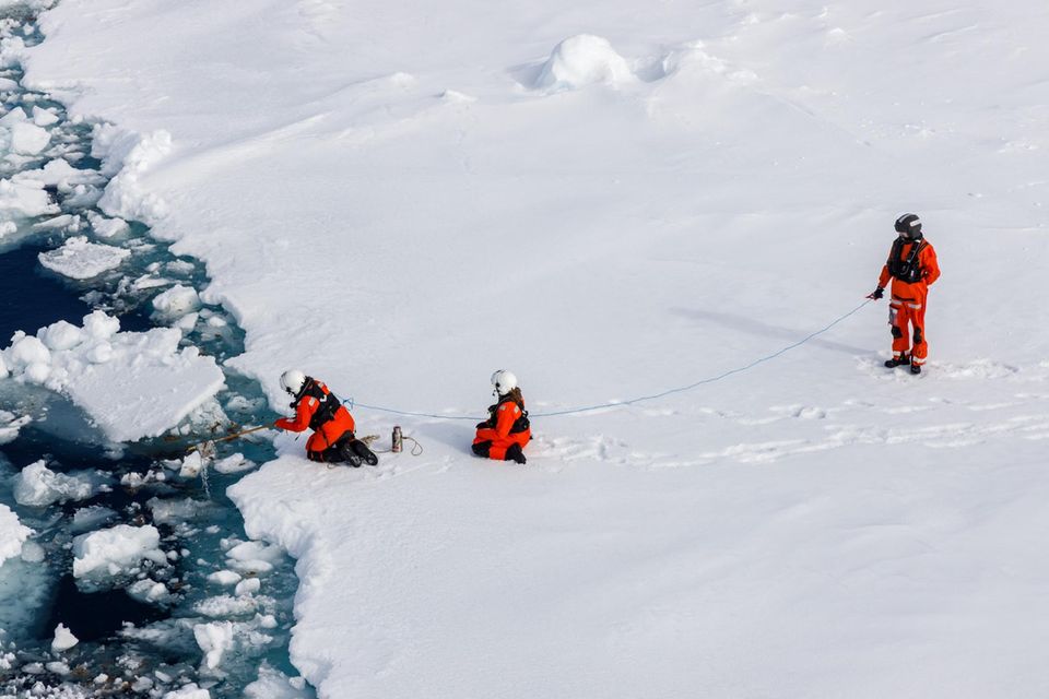 Drei Mitglieder eines Forschungsteams nehmen Proben der Eisalge Melosira arctica