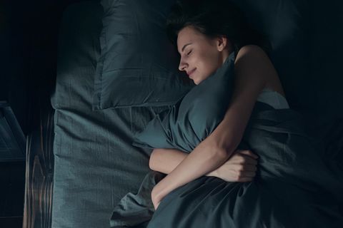 Eine Frau kuschelt sich ins Bett