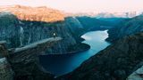 Eine Person steht im Abendlicht auf der Trolltunga
