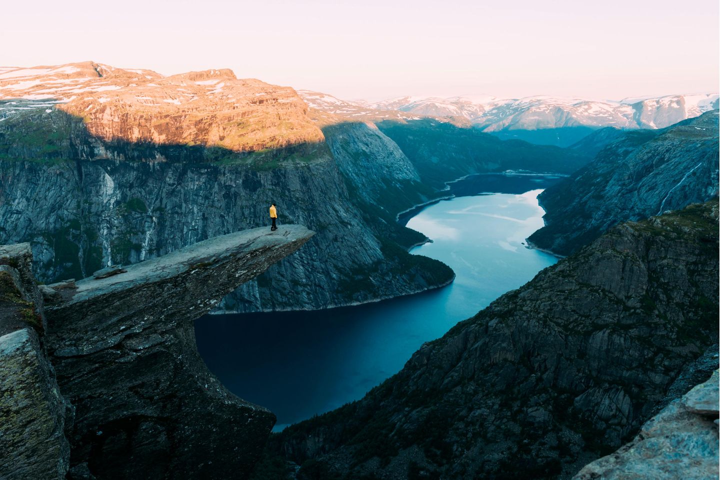 Eine Person steht im Abendlicht auf der Trolltunga