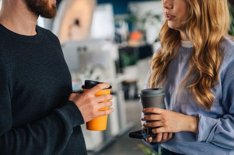 Zwei Menschen mit Kaffeebechern in der Hand