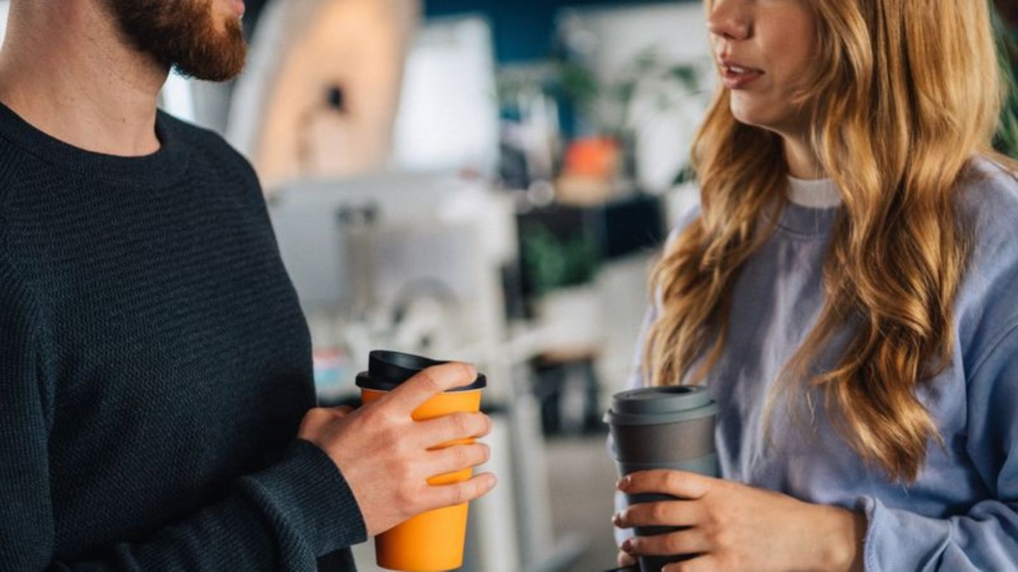 Zwei Menschen mit Kaffeebechern in der Hand