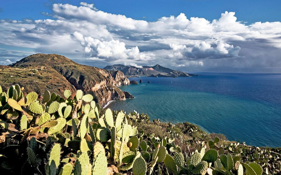 Die Äolischen Inseln: Reisende, die im Südwesten der Hauptinsel an diesem Aussichtspunkt stehen, dem Belvedere Quattrocchi, blicken über Kakteen hinweg bis nach Vulcano Reisende, die im Südwesten der Hauptinsel an diesem Aussichtspunkt stehen, dem Belvedere Quattrocchi, blicken über Kakteen hinweg bis nach Vulcano