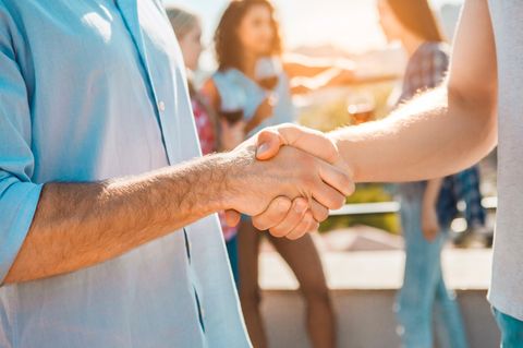 Zwei Hände schütteln sich auf einer Party