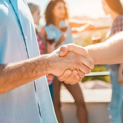 Zwei Hände schütteln sich auf einer Party