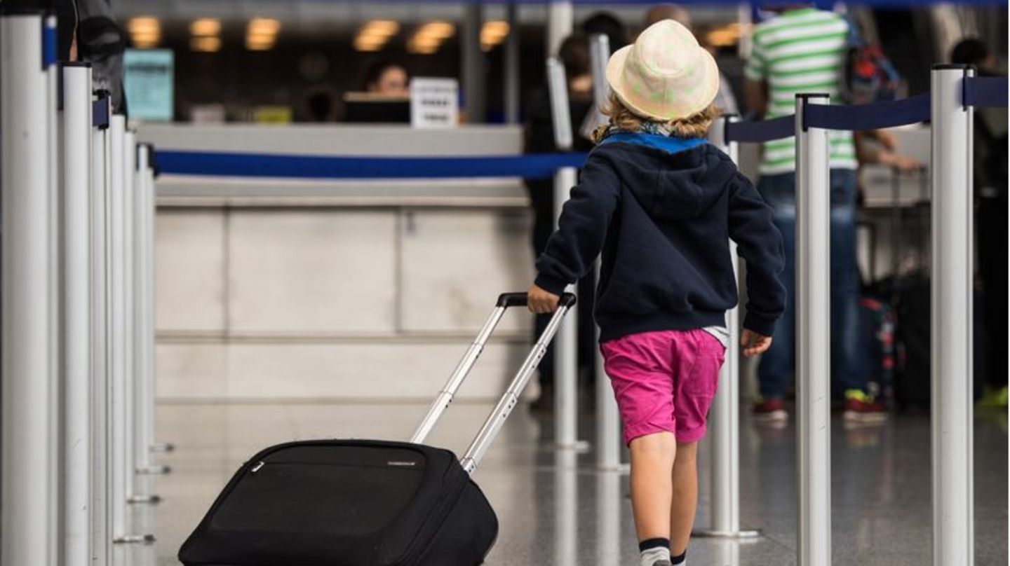 Ein Kind zieht am Flughafen einen Koffer hinter sich her