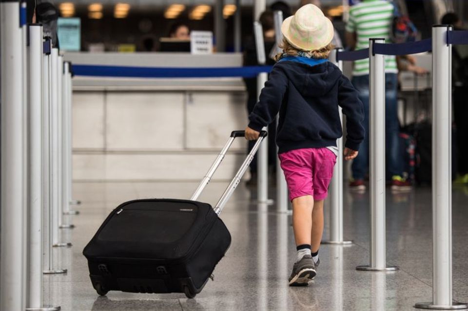 Ein Kind zieht am Flughafen einen Koffer hinter sich her