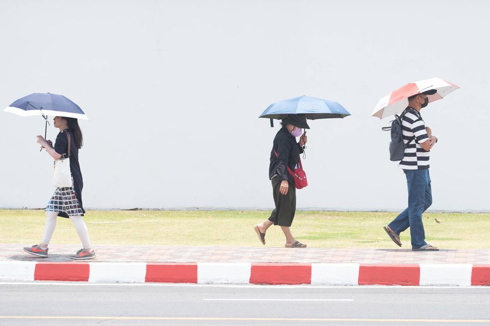 39 Grad in Bangkok: Menschen schützen sich in Thailand mit Hüten und Schirmen vor der extremen Hitze