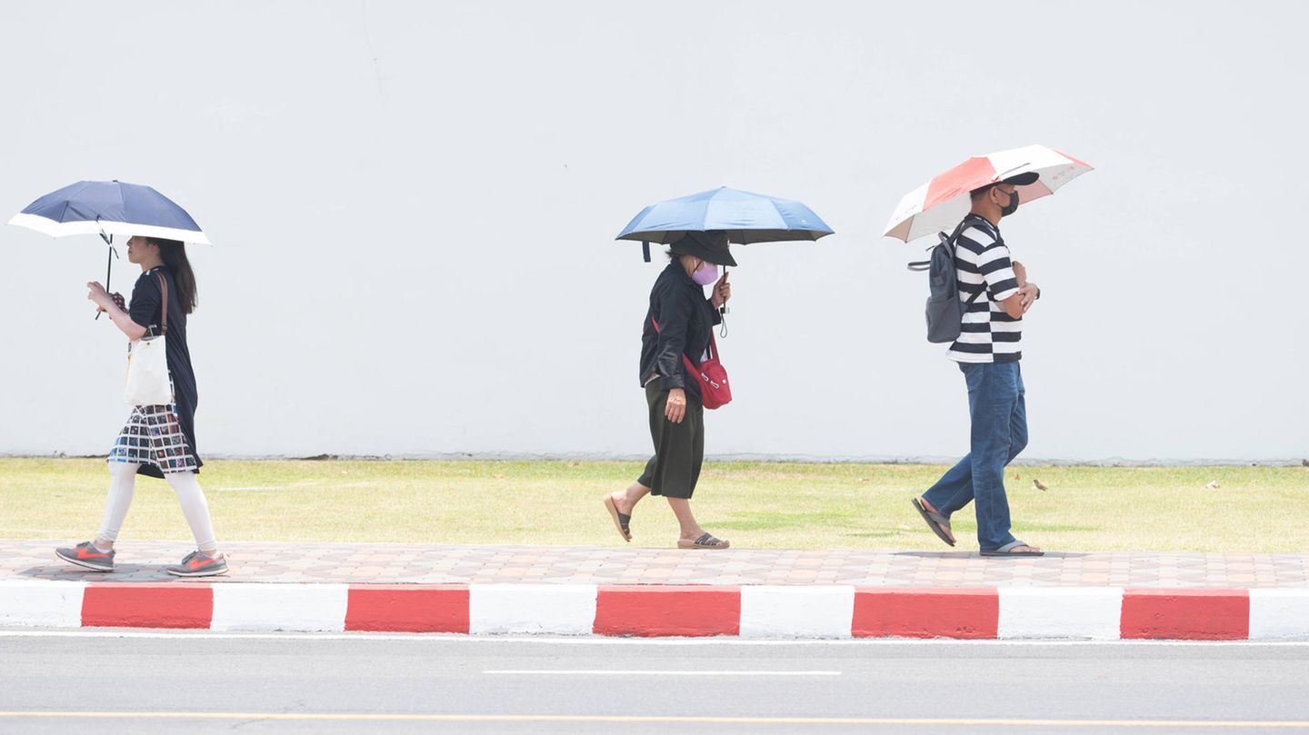 39 Grad in Bangkok: Menschen schützen sich in Thailand mit Hüten und Schirmen vor der extremen Hitze