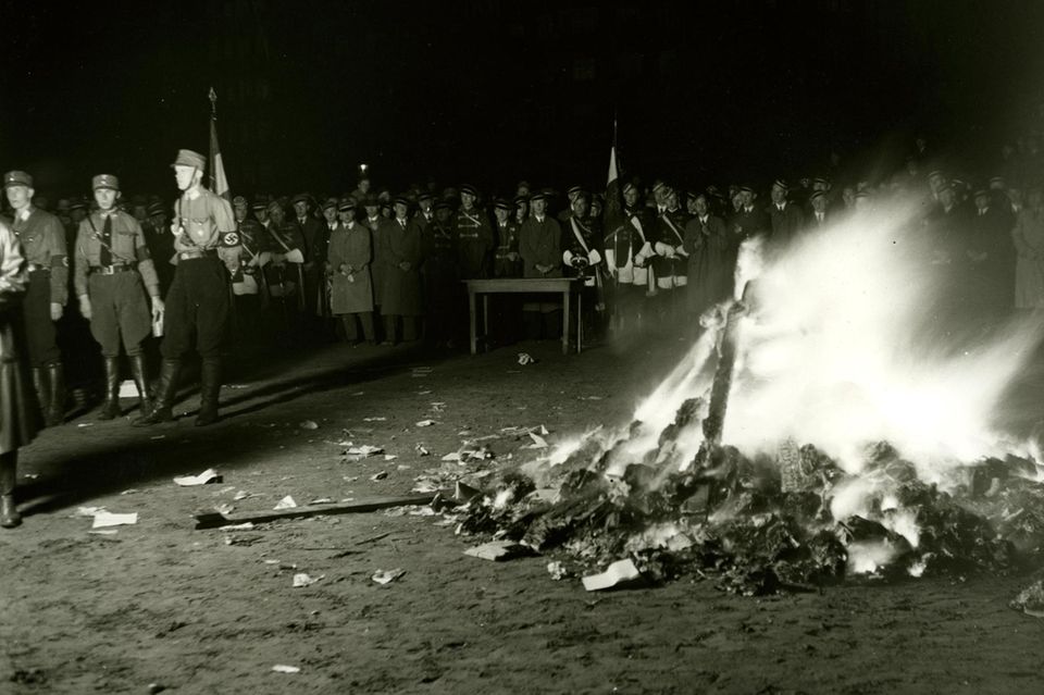Das Bild zeigt, wie Menschen (Nazis) Bücher verbrennen.