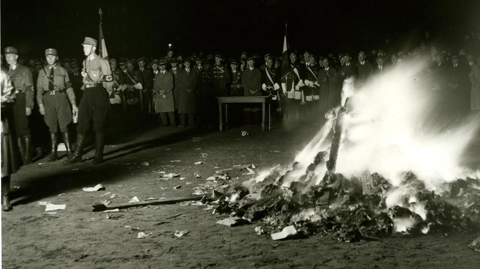 Das Bild zeigt, wie Menschen (Nazis) Bücher verbrennen. Das Bild zeigt, wie Menschen (Nazis) Bücher verbrennen.