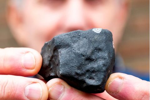 Hausbesitzer Wilfried Labusch mit einem kleinen Meteoriten, der niedergegangen ist. Foto: Daniel Bockwoldt/dpa