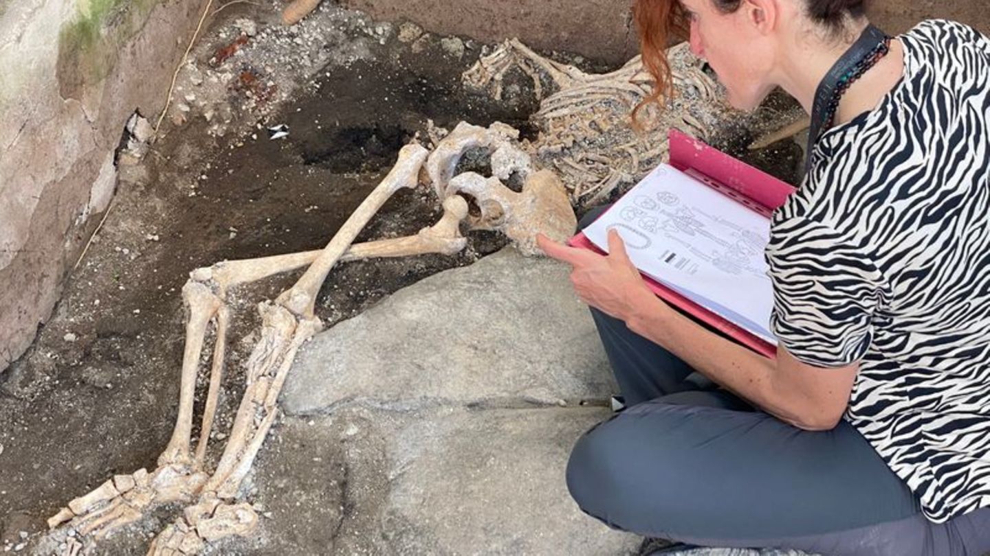 Eine Frau sitzt vor einem Skelett im Archäologiepark Pompeji