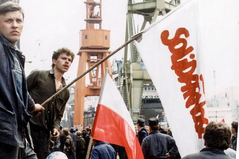 Entschlossen hält dieser Mann auf der Lenin-Werft eine Solidarność-Fahne. Dass ausgerechnet die Belegschaft in einem Vorzeigebetrieb des Landes die Arbeit niederlegt, trifft die Partei schwer