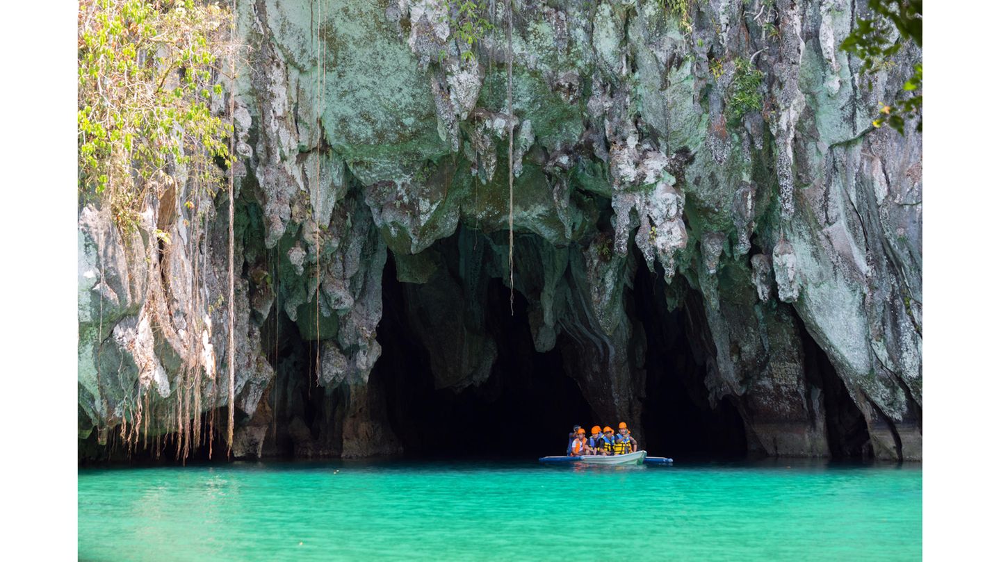 Puerto-Princesa-Subterranean-River-Nationalpark – Going Underground Ein kleines Boot mit mehreren Leuten am Eingang einer Höhle auf türkisfarbenem Wasser