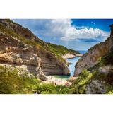 Blick von oben auf eine kleine Bucht mit klarem Wasser bei Sonnenschein