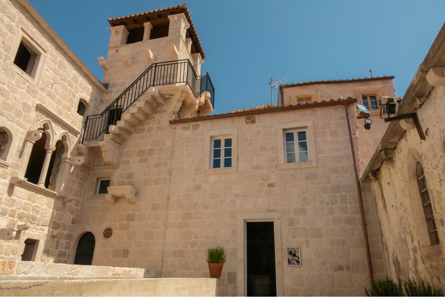 Helles Haus mit einem kleinen Turm bei strahlendem Sonnenschein