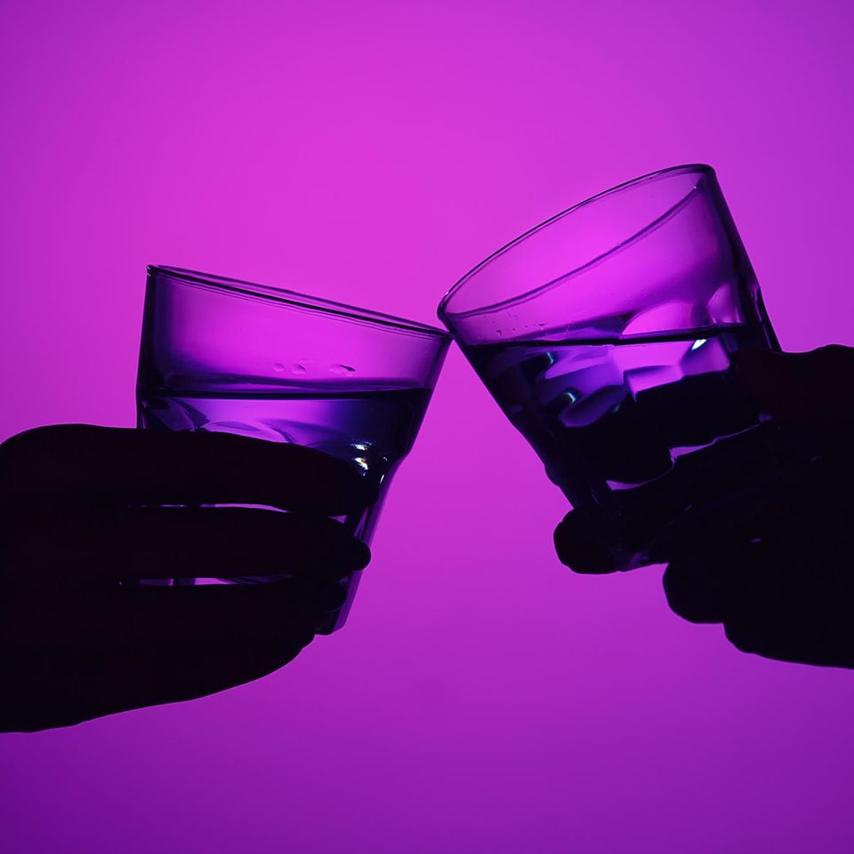 Zwei Hände mit Gläsern stoßen an