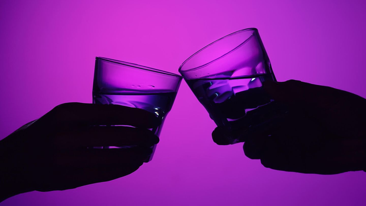 Zwei Hände mit Gläsern stoßen an