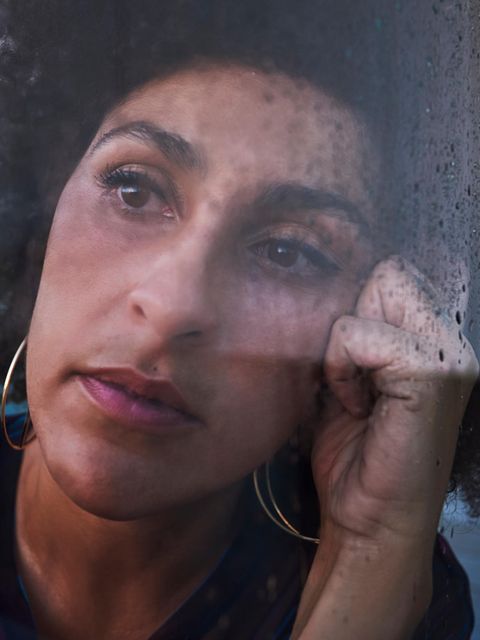 Eine Frau schaut nachdenklich, sie hat den Kopf auf die Hand gestützt