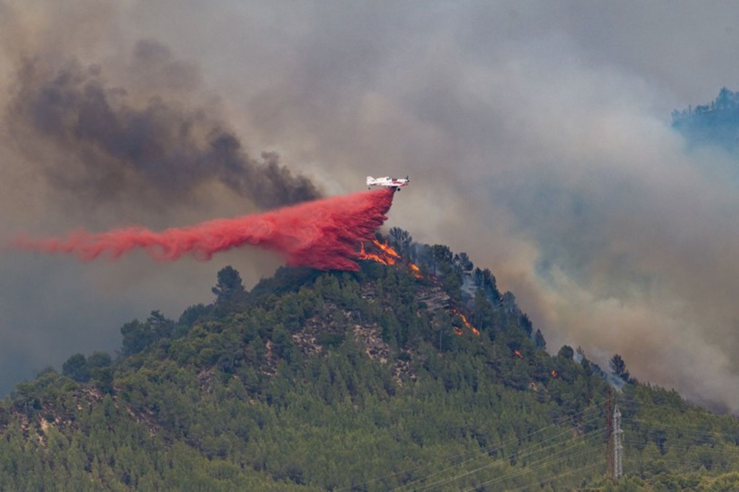 Ein Löschflugzeug wirft in Castellgali Löschmittel auf die Flammen eines Waldbrandes