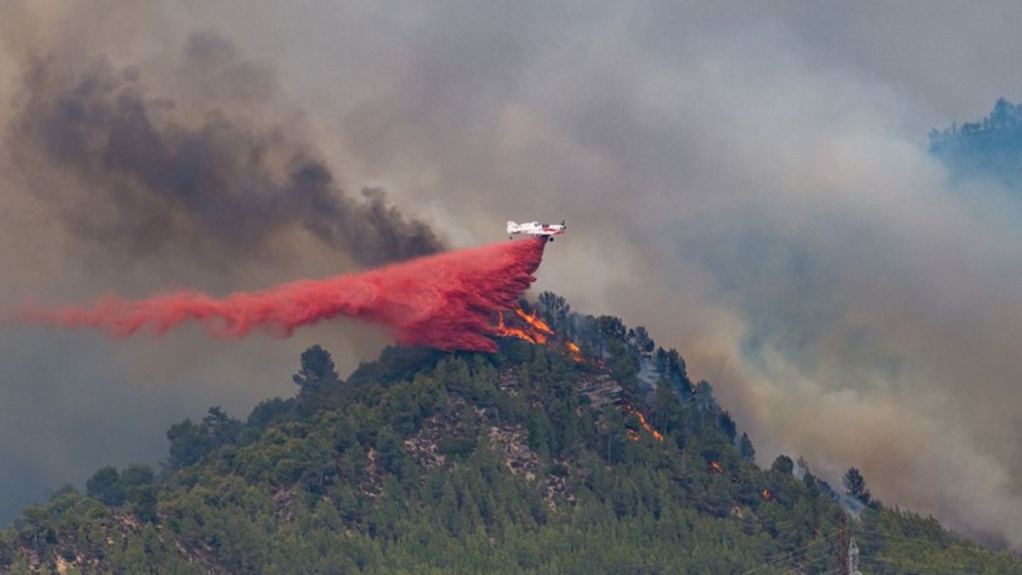 Ein Löschflugzeug wirft in Castellgali Löschmittel auf die Flammen eines Waldbrandes